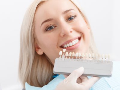White smile. Young attractive blond-haired woman by dentist and doctor matching filling for her teeth.